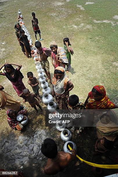 Flood affected Bangladeshi villagers queue for water in Koikhali on the outskirts of Satkhira some 400 km from Dhaka on June 3, 2009. Bangladesh and...