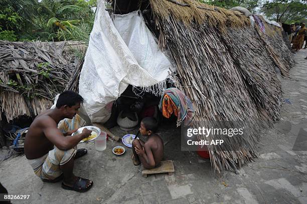 Displaced Bangladeshi villagers eat a meal outside a makeshift shelter by an embankment in Padmapukir on the outskirts of Satkhira some 400 km from...