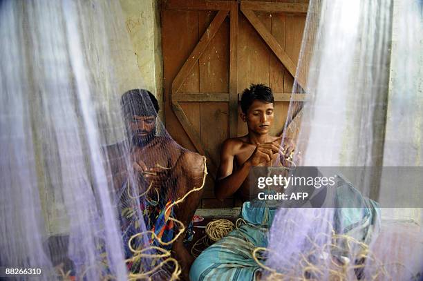 Displaced Bangladeshi villagers make nets near an embankment in Padmapukir on the outskirts of Satkhira some 400 km from Dhaka on June 3, 2009....