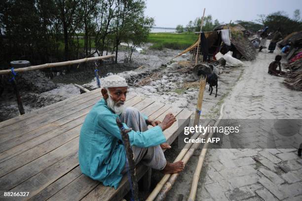 An elderly displaced Bangladeshi villager sits down by a makeshift shelter by an embankment in Padmapukir on the outskirts of Satkhira some 400 km...