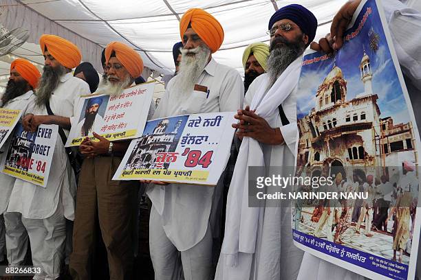Activists from radical Sikh organizations hold placards displaying images of the 1984 damage to the shrine Sri Akal Takht Sahib and a portrait of...