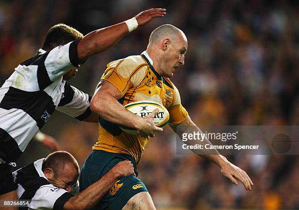 Stirling Mortlock of the Wallabies is tackled by Jerry Collins and Chris Whitaker of the Barbarians during the Nick Shehadie Cup match between the...