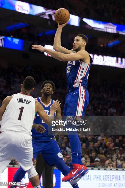 Ben Simmons of the Philadelphia 76ers shoots the ball against Evan Turner of the Portland Trail Blazers as Joel Embiid of the Philadelphia 76ers...