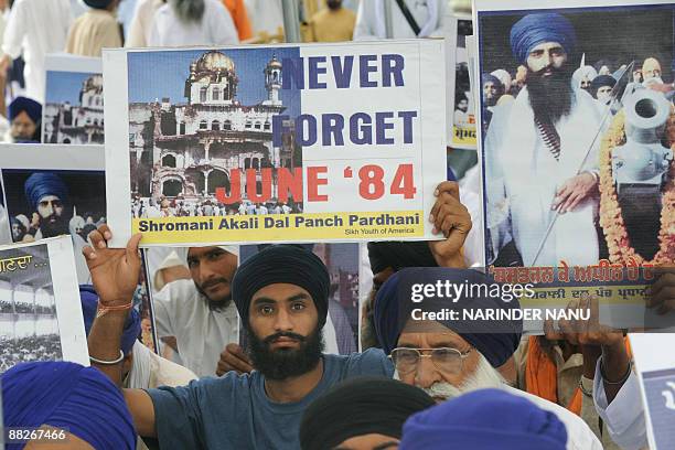 Activists from radical Sikh organizations hold placards displaying images of the 1984 damage to the shrine Sri Akal Takht Sahib and a portrait of...