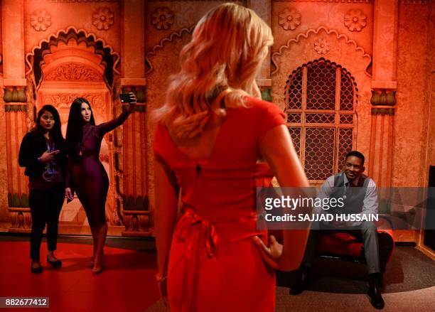 An Indian journalist poses with the wax statue of American actress Kim Kardashian and American actor Will Smith during the launch of Madame Tussauds...