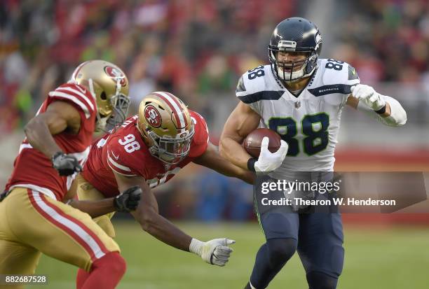 Jimmy Graham of the Seattle Seahawks looks to fight off the tackle of Ronald Blair and Antone Exum of the San Francisco 49ers during their NFL...