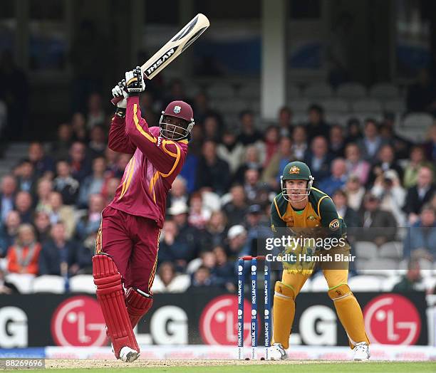 Chris Gayle of West Indies hits over long off with Brad Haddin of Australia looking on during the ICC Twenty20 World Cup match between Australia and...