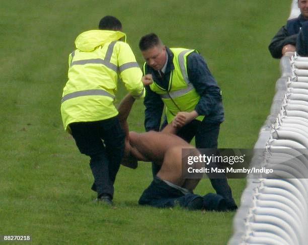 Streaker is held by racecourse stewards after running onto the track at the Epsom Derby Festivalat Epsom Racecourse on June 6, 2009 in Epsom, England.