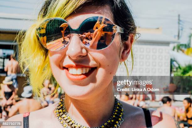 a girl wearing big reflective sunglasses smiling at a pool party - dyed shades imagens e fotografias de stock