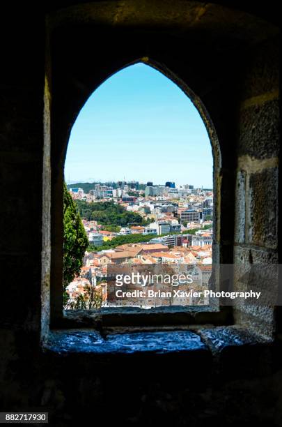 a stone window frames a city on a hill - brian sills stock-fotos und bilder