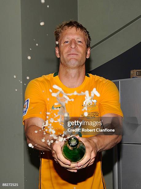 Vincenzo Grella of Australia celebrates by spraying non-alcoholic champagne in the changing rooms after Australia drew with Qatar to qualify for the...