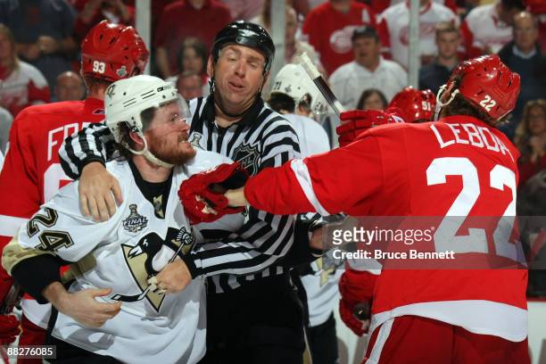 Linesman Pierre Racicot breaks up a scuffle between Matt Cooke of the Pittsburgh Penguins and Brett Lebda of the Detroit Red Wings during Game Five...