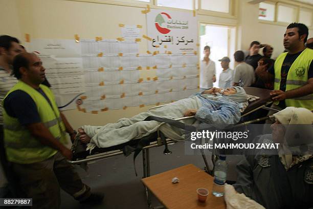 Lebanese paramedics carry a Lebanese elderly woman into a polling station to cast her vote in the southern port city of Sidon on June 7, 2009....