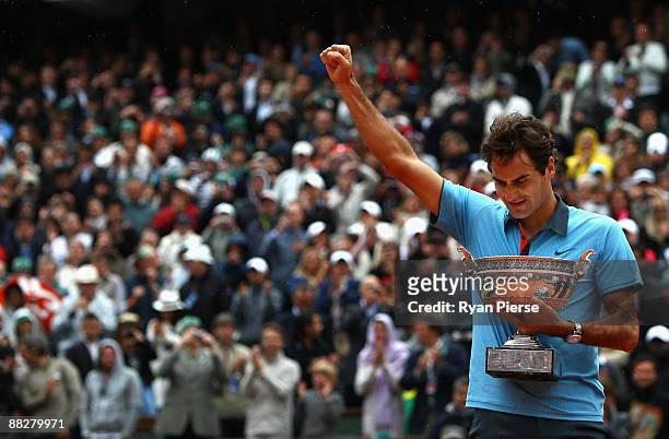 Roger Federer of Switzerland salutes the fans as he holds the trophy following victory during the Men's Singles Final match against Robin Soderling...