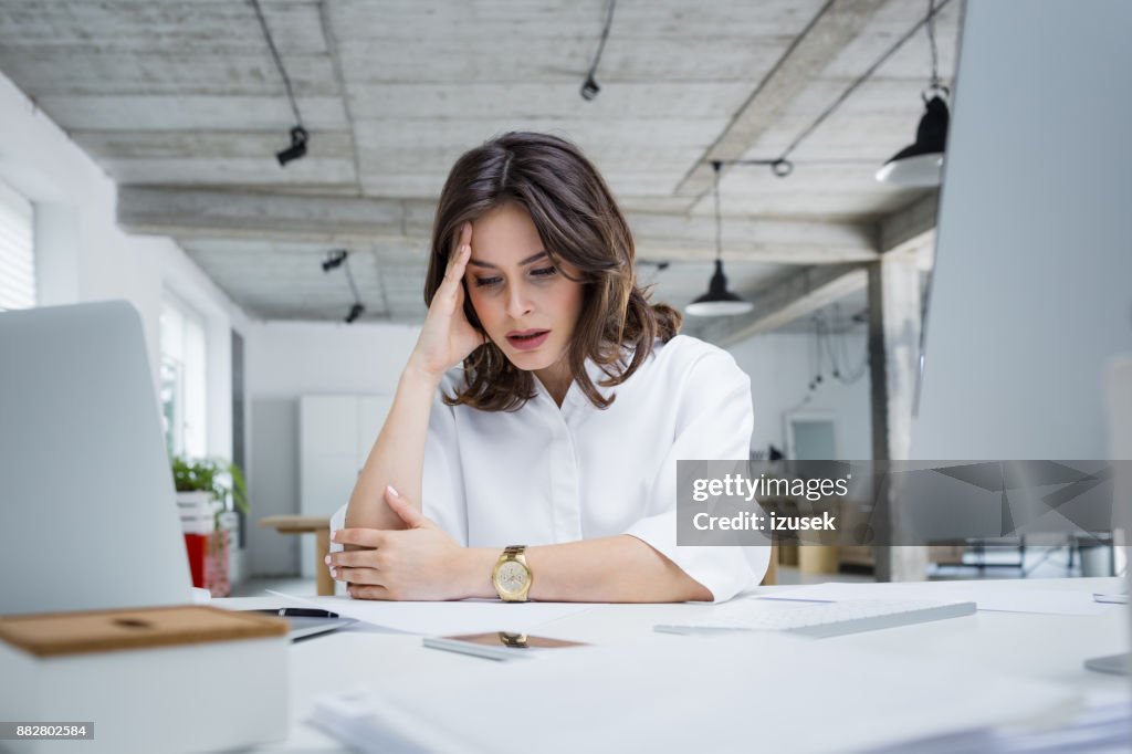 Female entrepreneur with headache sitting at desk