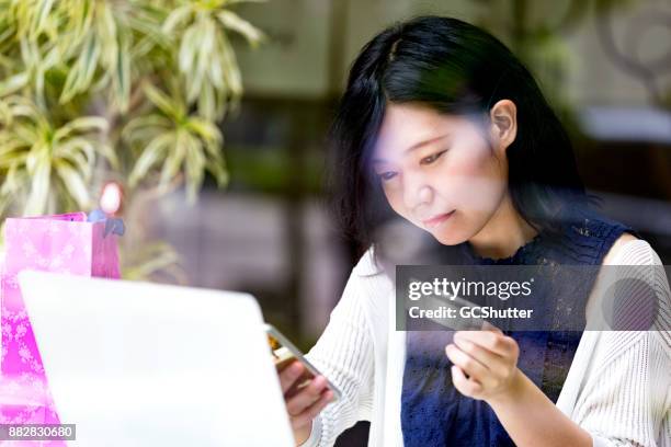 japanese girl using her smartphone and credit card to make an online payment - credit score stock pictures, royalty-free photos & images