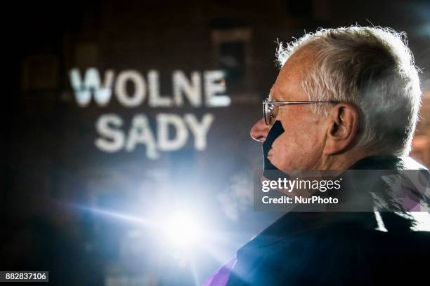 Man whose mouth is taped protests at the Main Square against government plans for sweeping changes to Polands judicial system. A sign screened in the...