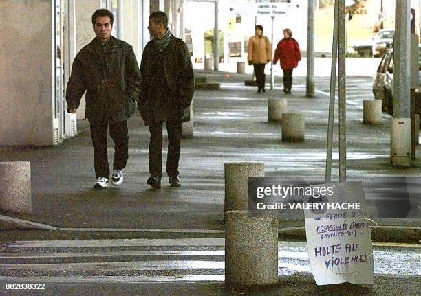 Deux personnes passent a côté de la pancarte déposée le 18 janvier dans la rue du centre commercial "Le Colombia" où une jeune femme a été poignardée...