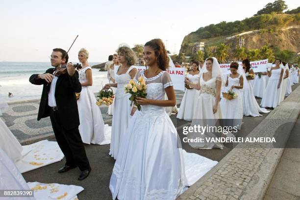 Group of fifty brides carrying banners march along Leblon beach in the southern part of Rio de Janeiro, 26 June 2003. The brides were protesting...