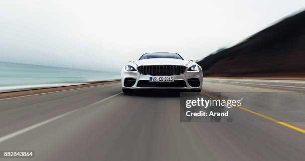 car driving on a road by sea - car sedan stock pictures, royalty-free photos & images