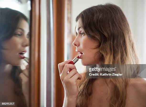young woman putting on lipstick - rossetto foto e immagini stock