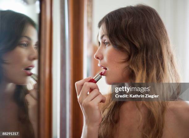 young woman putting on lipstick - applying makeup stock pictures, royalty-free photos & images