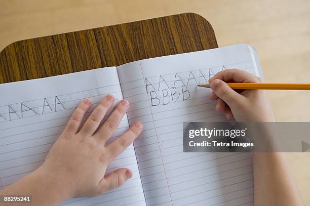 boy writing letters in classroom - kid hand raised stock pictures, royalty-free photos & images