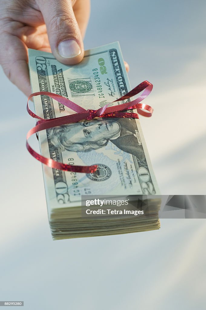 Man holding stack of money wrapped in ribbon