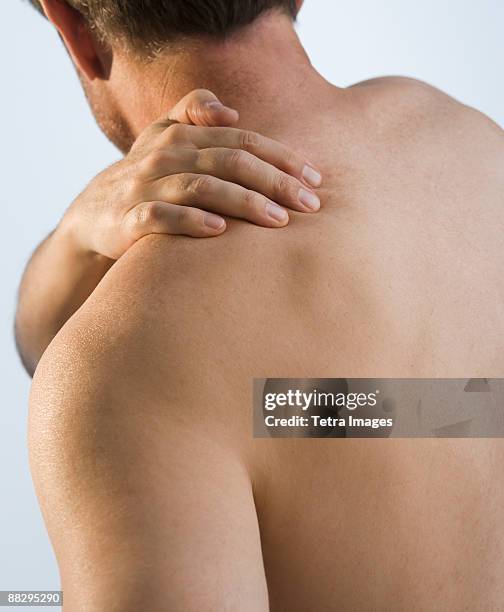 man rubbing sore shoulder - over shoulder man stockfoto's en -beelden