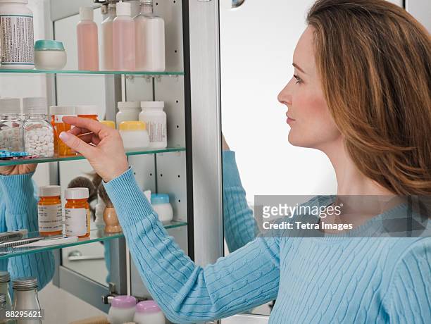 woman looking in medicine cabinet - armário de banheiro - fotografias e filmes do acervo