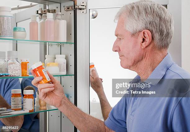 senior man looking at prescription - medicine cabinet 個照片及圖片檔