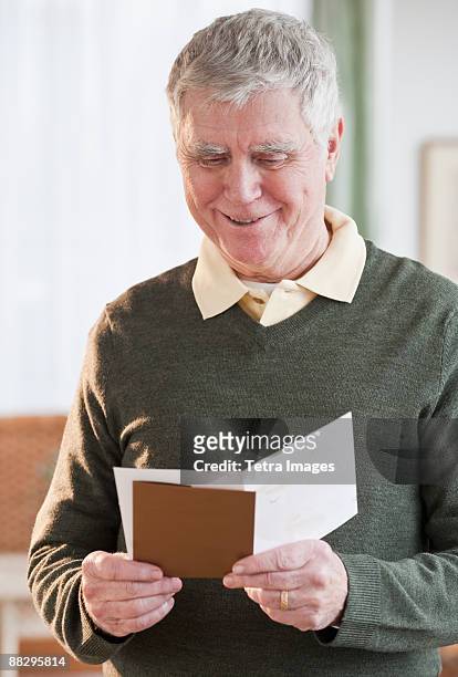 senior man reading greeting card - thinking of you card stock-fotos und bilder