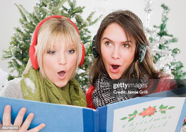 women singing christmas carols - christmas carols stock-fotos und bilder