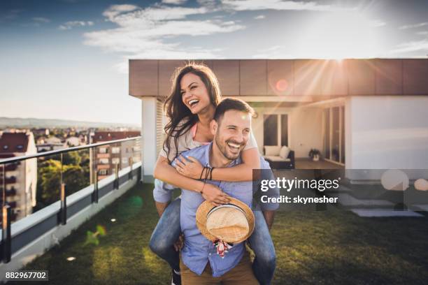 casal alegre se divertindo enquanto pegando carona em um terraço de cobertura. - women of penthouse - fotografias e filmes do acervo