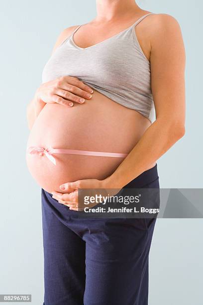pregnant womans belly wrapped in pink ribbon - its a girl ストックフォトと画像