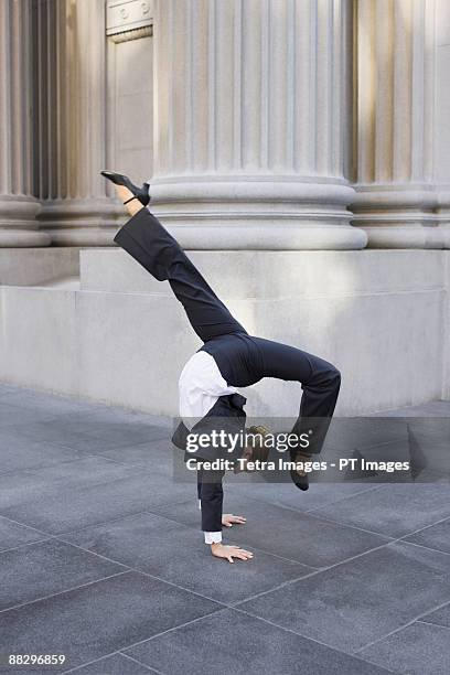 businesswoman dancing on urban sidewalk - businesswoman handstand stock-fotos und bilder