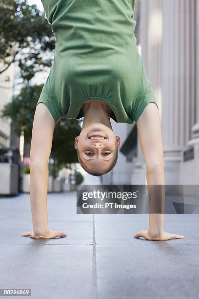 businesswoman doing handstand on urban sidewalk - businesswoman handstand stock pictures, royalty-free photos & images