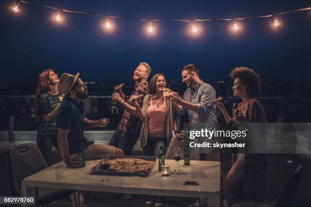 fröhliche freunde mit einem abendessen feiern in der nacht auf der terrasse. - speisen oder getränke zum mitnehmen stock-fotos und bilder