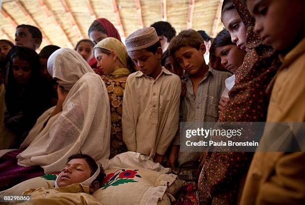 Mother hides her face as she mourns her son, Muneer Bakht who drowned while swimming in the canal, as children from the camp look on at the Chota...
