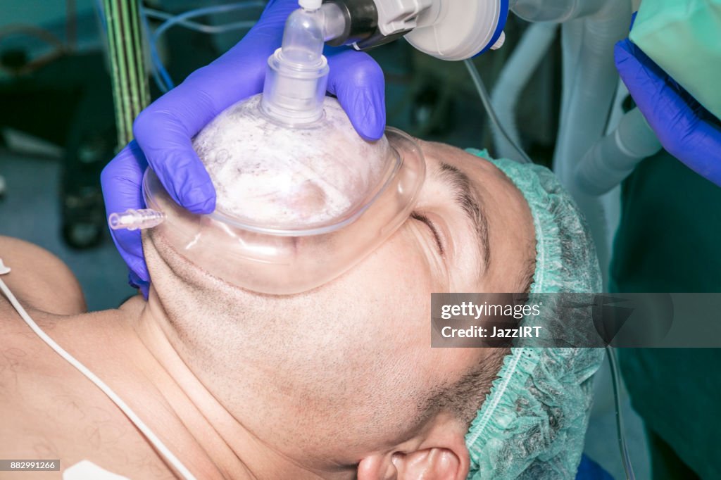 Anesthesiologist holding oxygen mask over patient during surgery