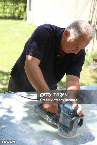 View of American artist Mike Solomon as he uses an electric sander outside his Long Island studio, East Hampton, New York, August 10, 2011.