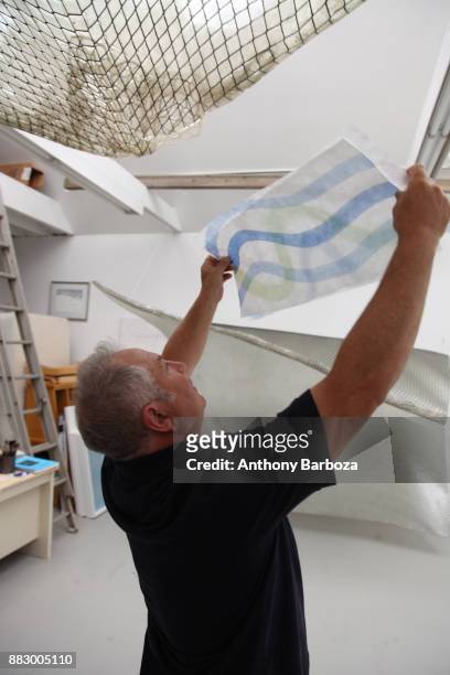 View of American artist Mike Solomon as he holds a painting up to the light in his Long Island studio, East Hampton, New York, August 10, 2011.