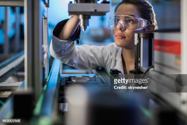 female engineer examining machine part on a production line. - engineer stock pictures, royalty-free photos & images