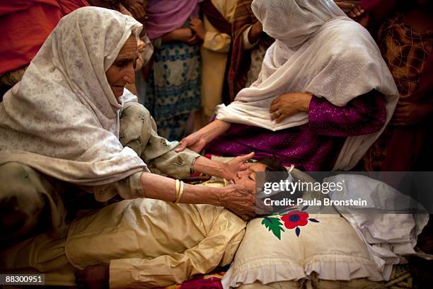 The grandmother, Shamsum fondly touches the face of Muneer Bakht the young boy drowned while swimming in the canal at the Chota Lahore camp June 8,...