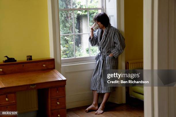 man looking out window in morning - accappatoio foto e immagini stock