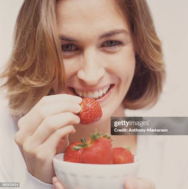 happy woman eating strawberries - anthony masterson stock-fotos und bilder