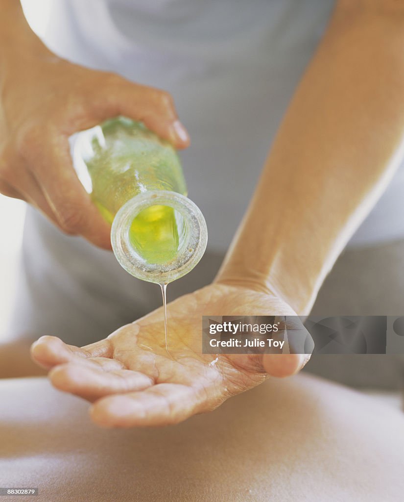 Masseur pouring liquid aloe vera into his hand