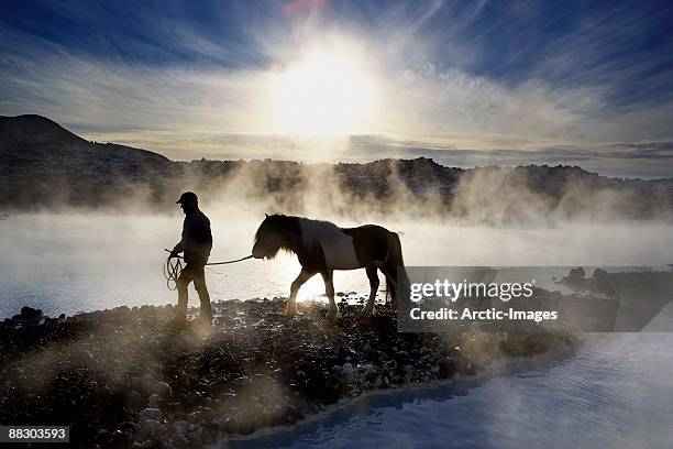 silhouette of person with horse in fog at dawn - blue lagoon ijsland stockfoto's en -beelden