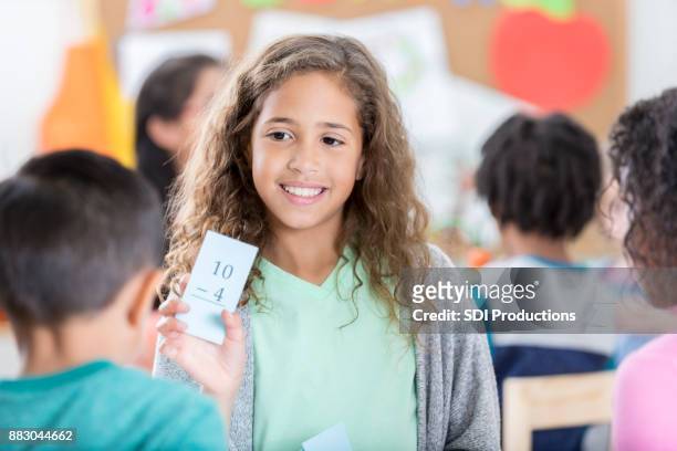 young elementary age girl quizzes friend with math flash card - flash card stock pictures, royalty-free photos & images