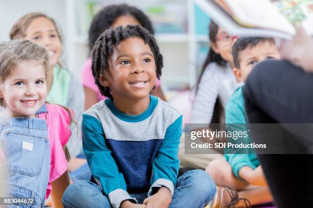 attentive little boy sits on floor during story time - child listening differential focus stock pictures, royalty-free photos & images